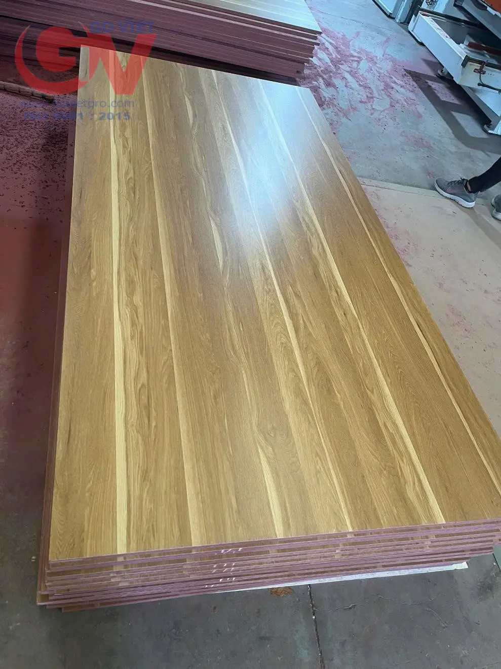 Các tấm ván MDF chống cháy phủ bề mặt vân gỗ với phần lõi nhuộm hồng đặc trưng tại xưởng sản xuất.